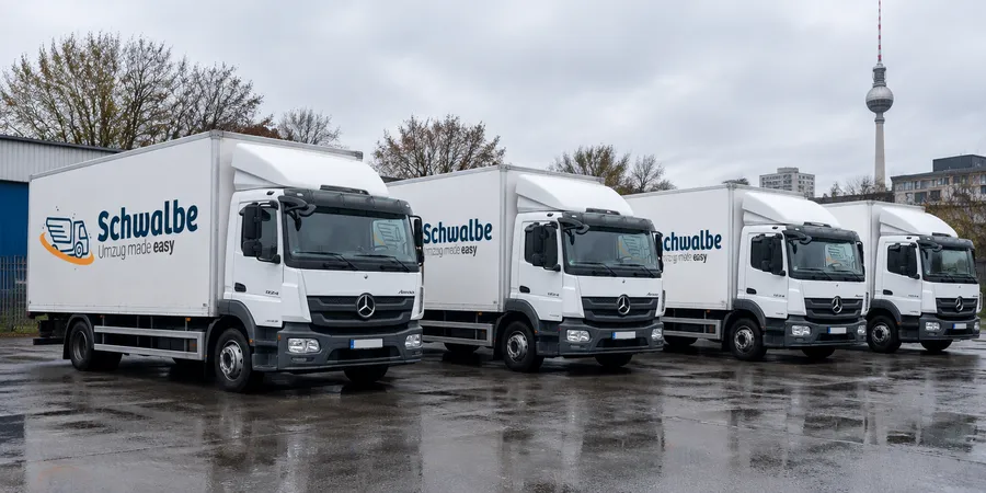 Vier Schwalbe-Umzugs-LKW (Mercedes Atego) mit Logo nebeneinander auf dem Betriebshof