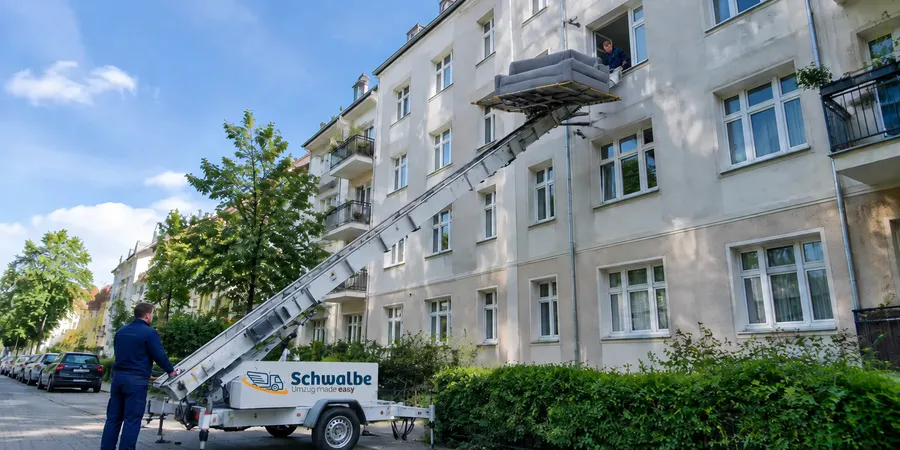 Schwalbe-Möbellift mit Logo hebt ein Sofa ins Obergeschoss